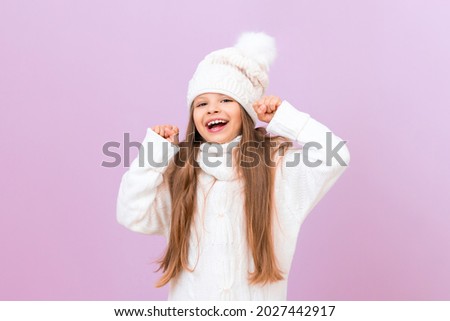 A girl in a warm winter sweater is very happy and smiles.