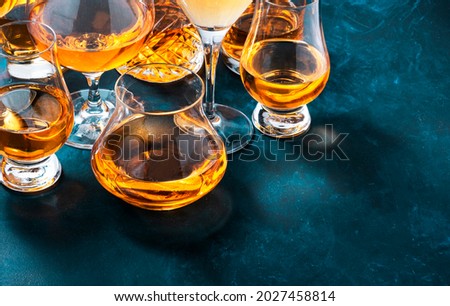 Strong alcohol drinks, hard liquors, spirits and distillates iset in glasses: cognac, scotch, whiskey and other. Blue background, top view  Royalty-Free Stock Photo #2027458814