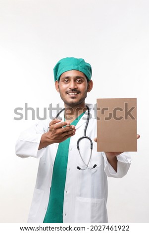 healthcare, profession and medicine concept - Young indian male doctor in uniform with board on white background.