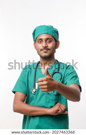 Doctor in a surgical dress with a stethoscope and showing thumbs up over white background.