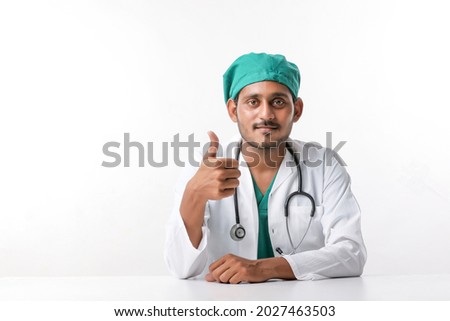Doctor in a white coat with a stethoscope and showing thumbs up over white background.