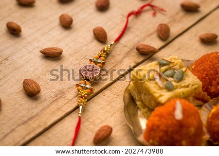 Raksha Bandhan background with an elegant Rakhi and Rice Grains on wooden textured background.