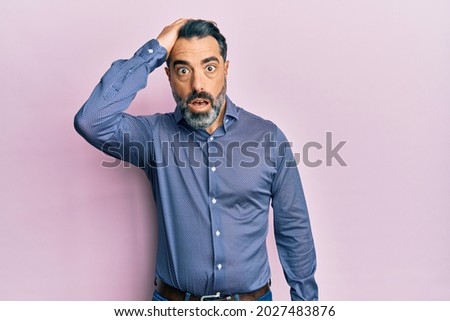 Middle age man with beard and grey hair wearing business clothes surprised with hand on head for mistake, remember error. forgot, bad memory concept.  Royalty-Free Stock Photo #2027483876