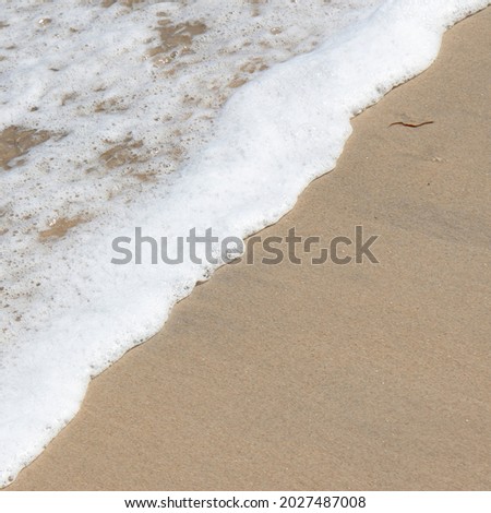 Wave of Atlantic Ocean, salt water and beach sand split diagonally, square picture