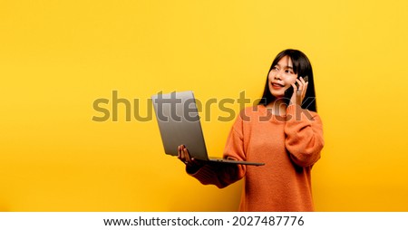 online communication concept asian girl use laptop at home yellow studio photo She is happy to spend her free time online while chatting with friends on social networks, shopping or working online.