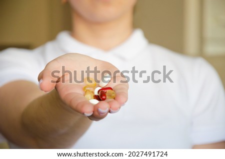 the girl holds in the palm of her hand multi-colored pills and holds out to the camera.