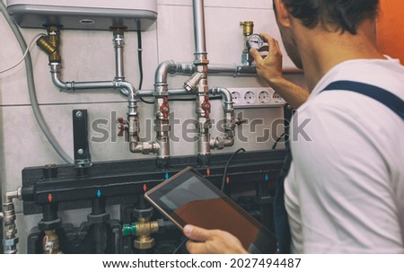 The technician checking the heating system in the boiler room with tablet in hand Royalty-Free Stock Photo #2027494487