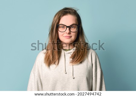 Pretty sleepy, disheveled student in glasses and a hoodie on a turquoise background. Royalty-Free Stock Photo #2027494742