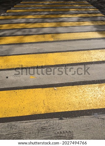 Yellow-and-white pedestrian crosswalk with the glare of the sun
