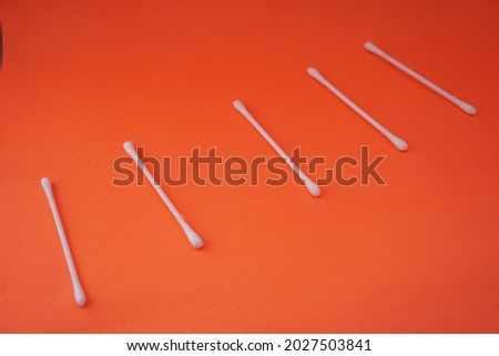 Stock photo of a pile of white cotton buds that are lined up and neatly arranged so that it looks aesthetic. Isolated on an orange background. Medical equipment Industry,design,website photo,Pattern