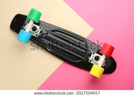 Black skateboard on color background, top view