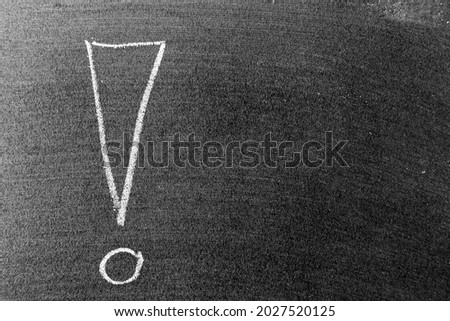 White color chalk hand drawing in exclamation mark with blank space shape on blackboard or chalkboard background