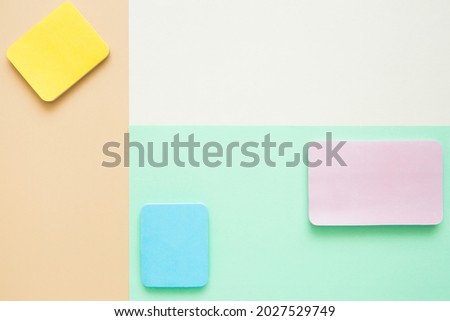 Blocks of bright colored blank stickers on a paper surface, top view. Geometric layout in pastel colors. Template, copy space.