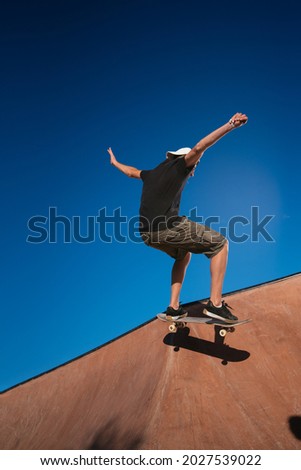 Young man in cap and shorts skateboarding on a concrete ramp. Royalty-Free Stock Photo #2027539022