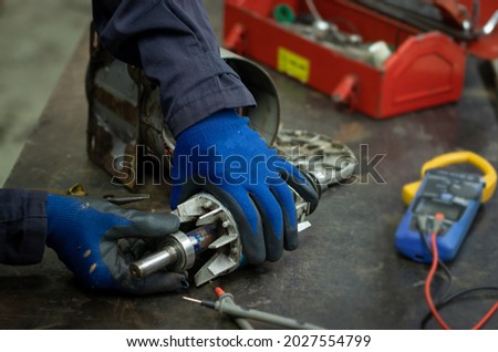 Close-up, repair and check the old electric motor bearing on the workbench by professional electrician, Concept of inspection or replacement of parts according to the monthly plan Royalty-Free Stock Photo #2027554799