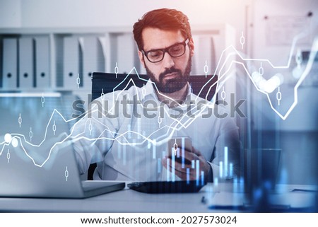 Businessman wearing white shirt is typing message on smartphone. Office workplace with calculator in the background. Financial chart and graph in the foreground. Concept of successful trading
