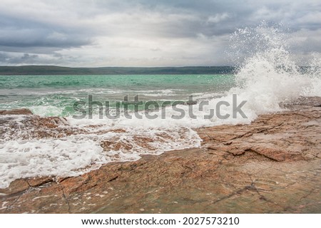 Dramatic scene with Sea waves, rocky seashore and blue clouds