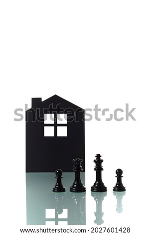 Conceptual photograph of two chess pieces metaphorically representing a black heterosexual couple forming a family with two children; with the silhouette of a house in the background. Space to copy.