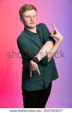 portrait of a red-haired guy in a green shirt and jeans on a colored background. the teenager dances, scares or pretends to be someone. cosplay drug addict