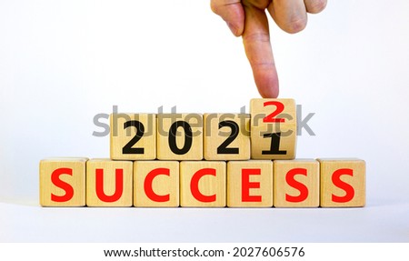 Planning 2022 success new year symbol. Businessman turns a wooden cube and changes words success 2021 to success 2022. Beautiful white background, copy space. Business, 2022 success new year concept.