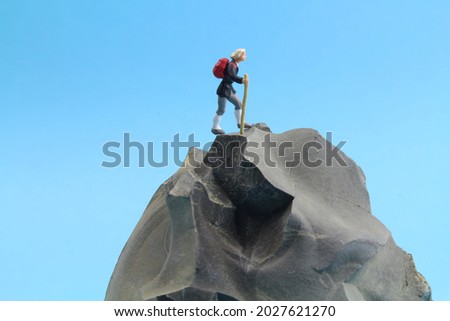 isolated stone with a figure of a hiker and blue background  Royalty-Free Stock Photo #2027621270