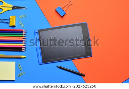School supplies, stationery on bicolor background, digital tablet, drawing, writing. Top view and copy space.