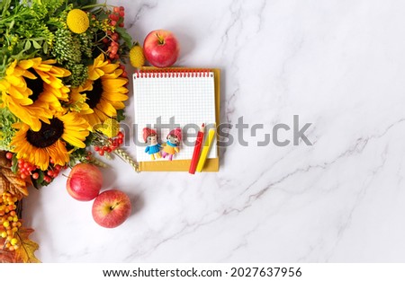 notepad, pencils, cute dolls, autumn flowers bouquet, apples on marble background. autumn seasonal composition. fall time concept. flat lay. copy space