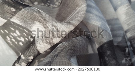 Light gray airy fabric with an abstract print with a blue tint, in folds (texture).
