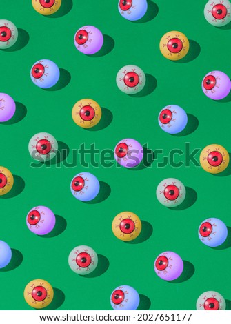 Pattern of colorful bloody eyeball Halloween candies on a vivid green background. Spooky concept. Royalty-Free Stock Photo #2027651177