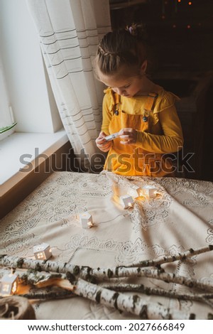 A cute sweet girl makes Christmas decorations from dried oranges, twigs and cones. Crafts for the holiday