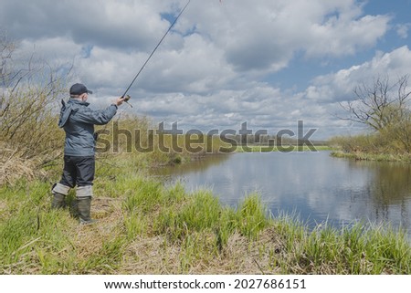 Fisherman throws spinning rod on the river bank. Autumn fishing.
