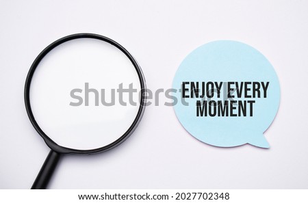 enjoy every moment speech bubble and black magnifier isolated on the yellow background.