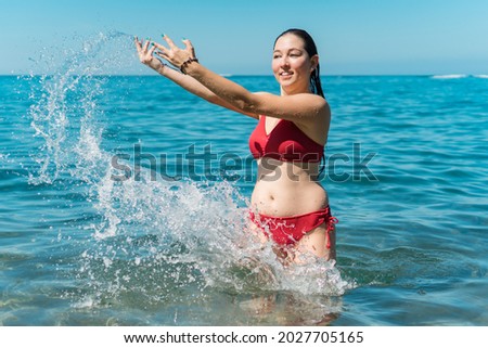 Girl having fun while bathing in the sea and splashing water