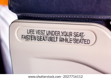 Attention announcement for passengers about emergency life vest and the seatbelt on the seat back inside the airplane cabin. Concept of takeoff, turbulence warning and safe landing of the aircraft