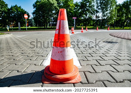 Red cones arranged in the street while stripes are painted on the road