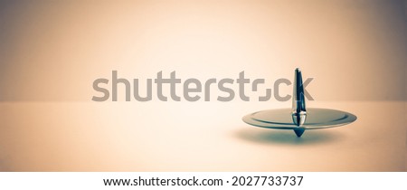 Metal spinning-top, rotation, warm light brown background