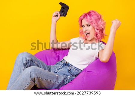 Photo of lucky funky young lady wear white t-shirt rising fist holding playstation smiling isolated yellow color background