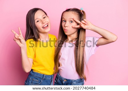 Photo of optimistic brunette blond girls show v-sign wear yellow pink t-shirt isolated on pink color background