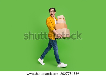Full size photo of young handsome good mood man go walk hold carton boxes move new house isolated on green color background