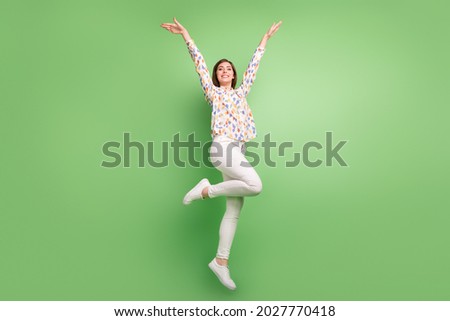 Full length photo of funny brunette hairdo young lady jump wear blouse trousers sneakers isolated on green background