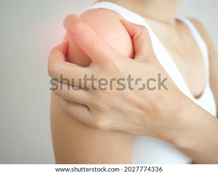 Asian woman suffering from shoulder pain on white background. closeup photo, blurred.