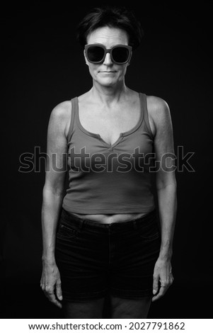 Studio shot of mature beautiful Scandinavian woman with short hair against black background in black and white