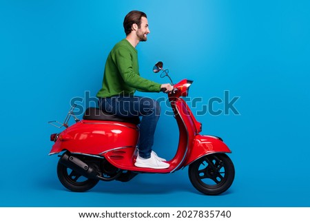 Full size profile side photo of smiling good mood man ride red moped travel freedom isolated on blue color background Royalty-Free Stock Photo #2027835740