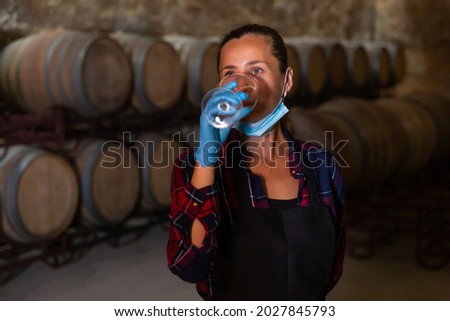 Woman in protective mask with glass of wine on wine factory