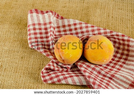 Ripe peaches on sackcloth. Two red fruits. Checkered fabric. Close-up. Selective focus.