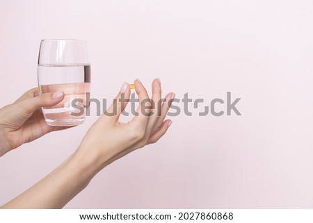 Woman holding pill and glass of water in hands taking emergency medicine, supplements or antibiotic antidepressant painkiller medication to relieve pain, meds side effects concept, close up view.  Royalty-Free Stock Photo #2027860868