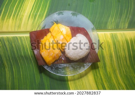 Mango sticky rice served on a spotted banana leaf by the pool.
speckled banana leaves in the background.
beautiful green and yellow color of nature background. food and restaurant concept.