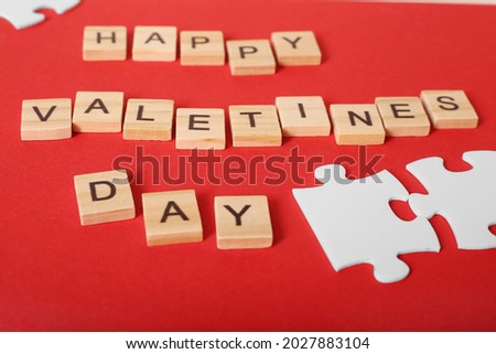 The inscription from letters Valentine's Day with white puzzles on the background. Congratulatory postcard. Declaration of love. St. Valentine's Day.