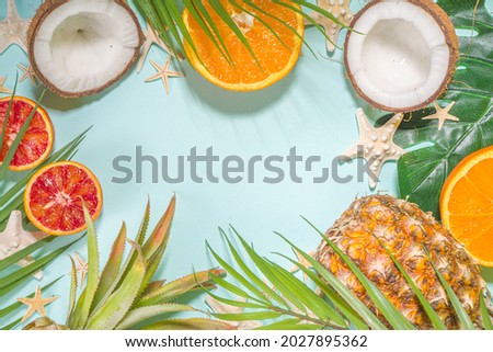 Summer vacation flat lay with with pineapple coconut orange fruit, palm leaves and sea shell, over light blue background copy space top view