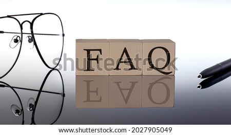 Close-up Of FAQ Wooden Blocks on black background with glasses and pen